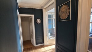 A hallway with dark walls, white trim, and a wooden floor. There are two doors, one leading to a room and another to a balcony.