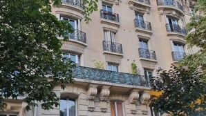 A building with ornate balconies, a black gate, and outdoor seating.