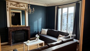 A living room with a dark blue wall, a fireplace, a sofa, a coffee table, and a chandelier.