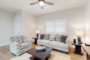 A living room with a sofa, armchair, coffee table, and a ceiling fan. - Chic dog-friendly condo with pool, central AC, washer/dryer, & grill (Tucson)