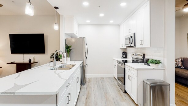 A modern kitchen with white cabinetry, stainless steel appliances, and a large island.