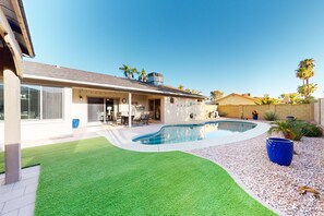 A residential property with a swimming pool, a patio with outdoor furniture, and a well-maintained lawn. - Updated home with enclosed yard, pool, grill, full kitchen, games, W/D, & AC (Mesa)