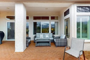 A covered patio area with a sofa set, a chair, and a table. - Mountain-view home with on-site pool/hot tub, private yard, patio (Oro Valley)