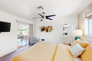 A hotel room with a bed, a ceiling fan, a TV, a desk, and a window. - Bright, Family-Friendly Home with Private Firepit, Heated Outdoor Pool, Pool Spa (Palm Springs)
