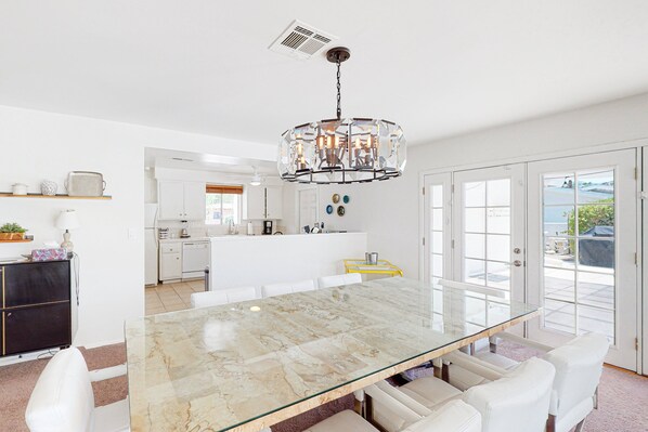 A modern kitchen with white cabinets, a marble island, and a hanging light fixture. - Bright, Family-Friendly Home with Private Firepit, Heated Outdoor Pool, Pool Spa (Palm Springs)