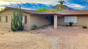 A single-story house with a sloped roof, a large cactus in the front yard, and a mountain in the background. - Sunlit & spacious desert villa with patio, games, & fire pit - near golf & parks (Paradise Valley)