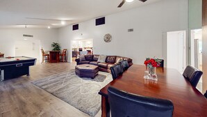 A spacious living room with a pool table, a large wooden dining table, and a ceiling fan. - Sunlit & spacious desert villa with patio, games, & fire pit - near golf & parks (Paradise Valley)
