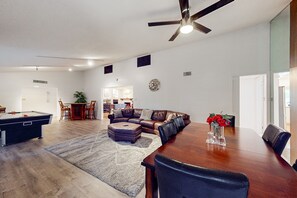 A spacious living room with a pool table, a large wooden dining table, and a ceiling fan. - Sunlit & spacious desert villa with patio, games, & fire pit - near golf & parks (Paradise Valley)