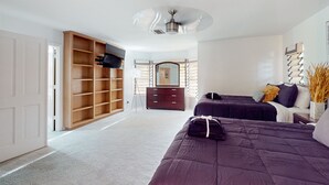 A bedroom with a large wardrobe, two beds, a ceiling fan, and a mirror. - Sunlit & spacious desert villa with patio, games, & fire pit - near golf & parks (Paradise Valley)