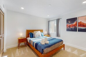 A neatly made bed with a blue and beige bedspread, two bedside lamps, and a wooden nightstand with a drawer. - Sonoran Starlight condo with large backyard, pool and jacuzzi (Scottsdale)