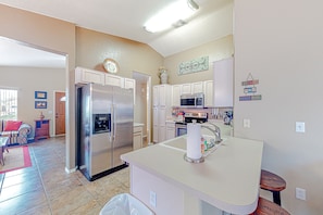 A kitchen with white cabinets, a stainless steel refrigerator, a microwave, and a sink.