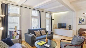 A modern living room with a grey sofa, a round coffee table, and a wooden floor. - AN AUTHENTIC PARISIAN STAY IN THE MOST LOVED NEIGHBOURHOOD  - RUE DU FOUR (Paris)