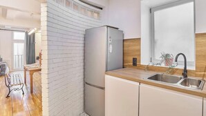 A compact kitchen with a refrigerator, a sink, and a window. - AN AUTHENTIC PARISIAN STAY IN THE MOST LOVED NEIGHBOURHOOD  - RUE DU FOUR (Paris)