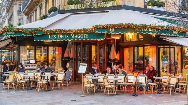 An outdoor cafe with tables and chairs, a sign reading "LES DEUX MAGOTS," and a menu board. - AN AUTHENTIC PARISIAN STAY IN THE MOST LOVED NEIGHBOURHOOD  - RUE DU FOUR (Paris)