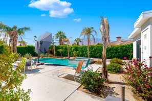 A pool area with lounge chairs, a white building, and palm trees. - Modern Palm Springs Beauty with Luxe Private Pool & Mountain Views (Palm Springs)