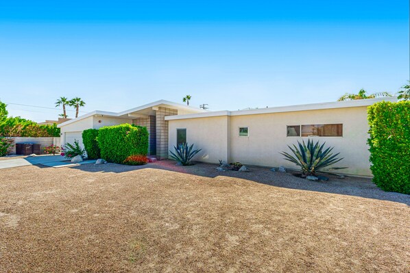A modern two-story house with a driveway, well-maintained landscaping, and a clear sky. - Modern Palm Springs Beauty with Luxe Private Pool & Mountain Views (Palm Springs)