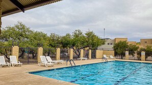 Una piscina con sillones de descanso y un área techada.