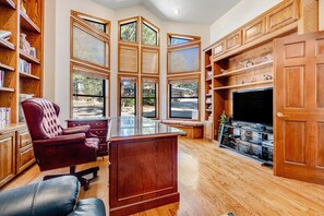 Un salon spacieux avec un grand meuble de rangement en bois servant de centre de divertissement, un fauteuil en cuir confortable et une table basse avec un plateau en verre.