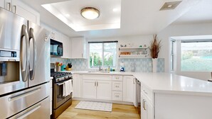 Eine moderne Küche mit Edelstahlgeräten, weißen Schränken und einem großen Fenster für natürliches Licht.