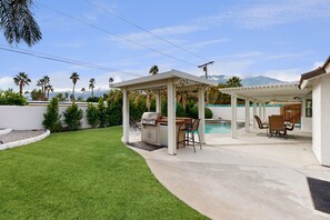 A backyard with a barbecue area, outdoor seating, and a swimming pool. - Views, tranquility, private pool and spa, outdoor kitchen (Palm Springs)