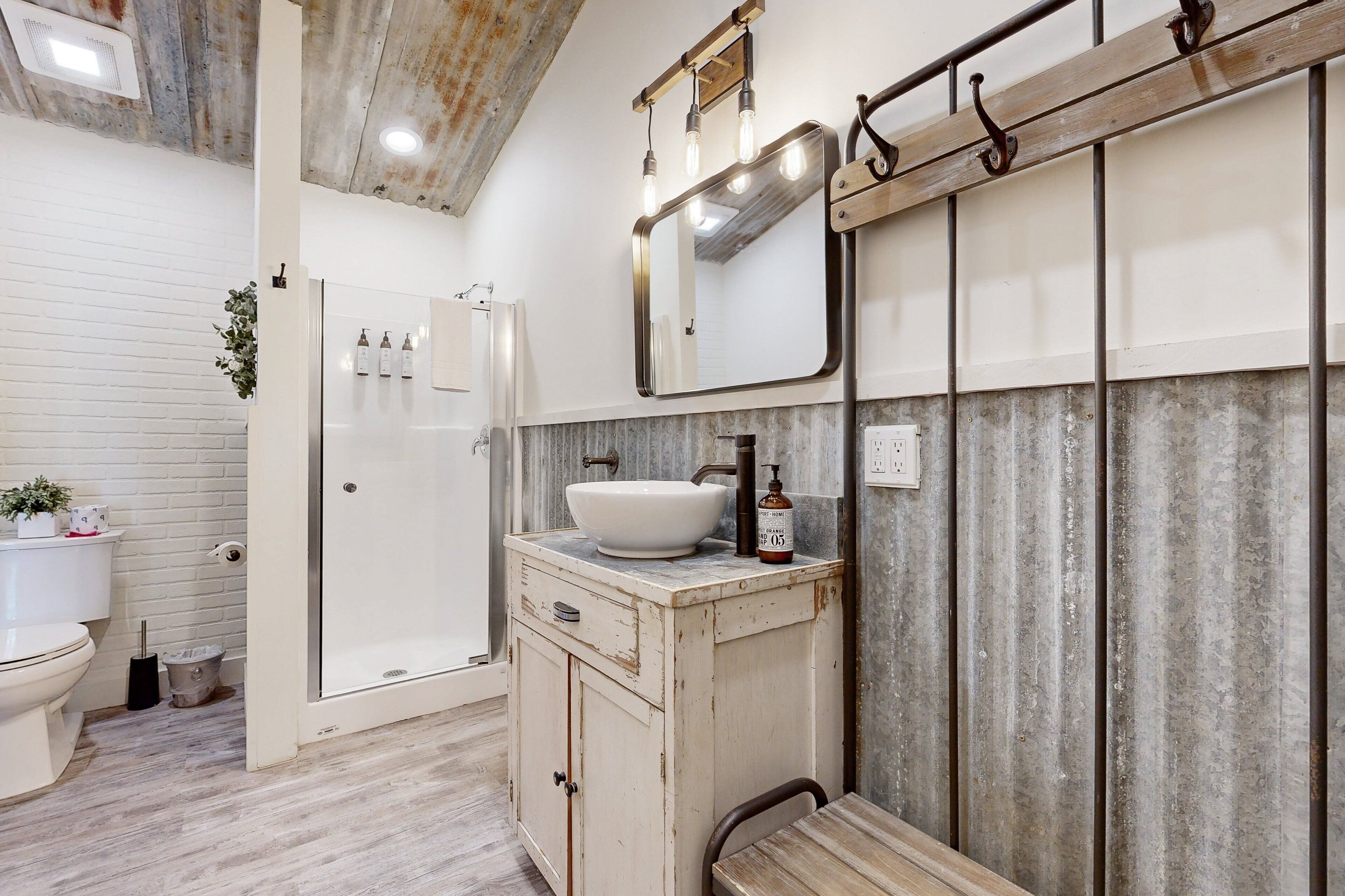 A bathroom with a white sink, a mirror, and a shower.