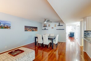 A dining area with a wooden floor, a table with chairs, and a ceiling fan. - Centrally located retreat with pool, Ping-Pong, balcony, full kitchen, W/D, & AC (Tempe)