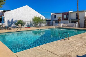 A swimming pool with clear blue water, surrounded by lounge chairs and a white building with a modern design. - Centrally located retreat with pool, Ping-Pong, balcony, full kitchen, W/D, & AC (Tempe)