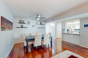 A dining area with a dark wooden table and patterned chairs, a ceiling fan, and wall-mounted shelves with decorative items. - Centrally located retreat with pool, Ping-Pong, balcony, full kitchen, W/D, & AC (Tempe)