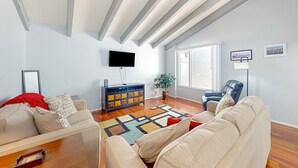 Een moderne woonkamer met een bank, salontafel, televisie, kast en groot raam.