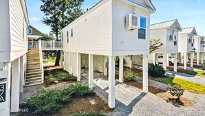 A residential building with a raised deck, a covered staircase, and a small garden area. - The Pass Picture Book (Pass Christian)