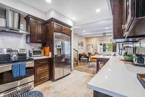 A modern kitchen with dark wooden cabinets, stainless steel appliances, and a white countertop. - Dog-Friendly Getaway with Fast WiFi, Wood-Burning Fireplace, & Furnished Deck (Idyllwild)