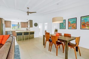 A modern kitchen with a central island, wooden dining table with chairs, and a ceiling fan. - Racquet Club East Home with Modern Flair | Pool, Spa & Outdoor Living (Palm Springs)
