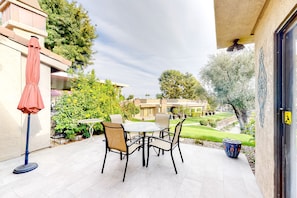 An outdoor patio with a table and chairs, surrounded by greenery and a view of a residential area. - Dreamy Desert Hideaway | Pool, Hot Tub & 2 Patios - Near Dining, Shops & Golf (Palm Desert)