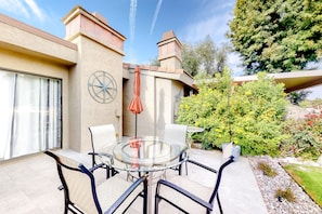 A patio with a glass table and chairs, a compass decoration, and a red umbrella. - Dreamy Desert Hideaway | Pool, Hot Tub & 2 Patios - Near Dining, Shops & Golf (Palm Desert)