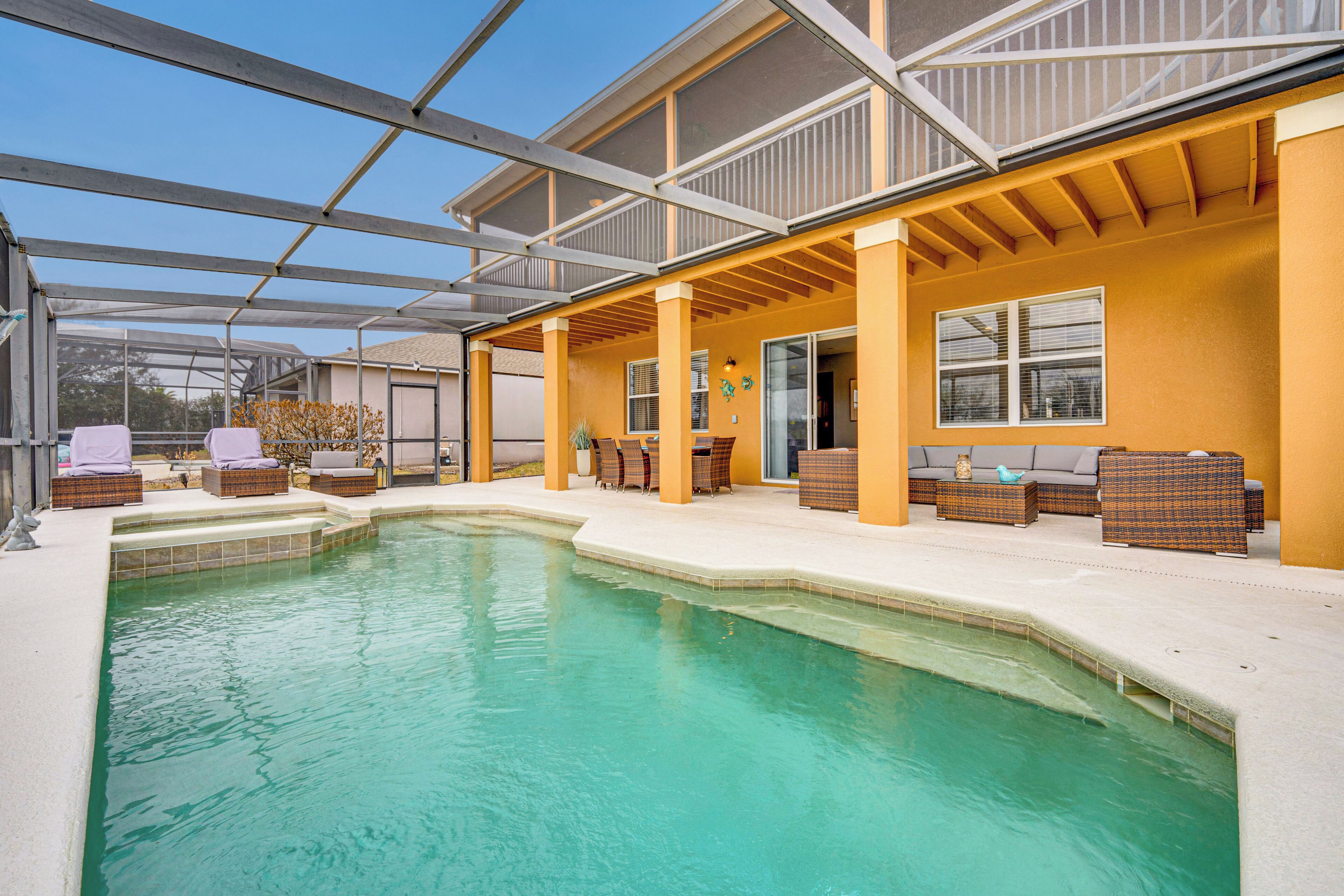 Un espace piscine doté d’un patio couvert, de chaises longues et offrant une vue dégagée sur la piscine.