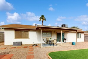Une maison de plain-pied avec un patio, un palmier et une allée gravillonnée.