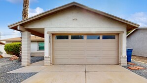 Una casa a un piano con garage, un piccolo portico e una palma.