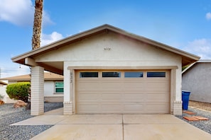 Une maison de plain-pied avec un garage, un petit porche et un palmier.