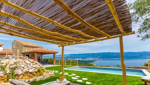 A poolside area with a pergola, lounge chairs, a stone wall, and a view of a lake and mountains. - Villa Mare - OneBedroom Villa with Pool (Vrbnik)