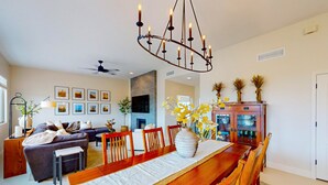 A spacious living room with a large wooden dining table, comfortable seating, and a modern chandelier. - Dog-friendly home with mountain views, ample outdoor space, & washer/dryer (Tucson)