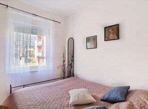 A bedroom with a bed, a window with sheer curtains, and two framed pictures on the wall. - Monika Seaside Apartment - OneBedroom Apartment With Balcony (Kastel Luksic)