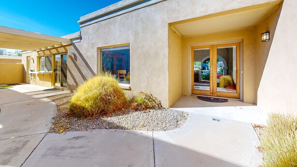 A modern building with a beige facade, large windows, and a covered entrance. - Gorgeous home with private pool, grill, games, near golf (Scottsdale)
