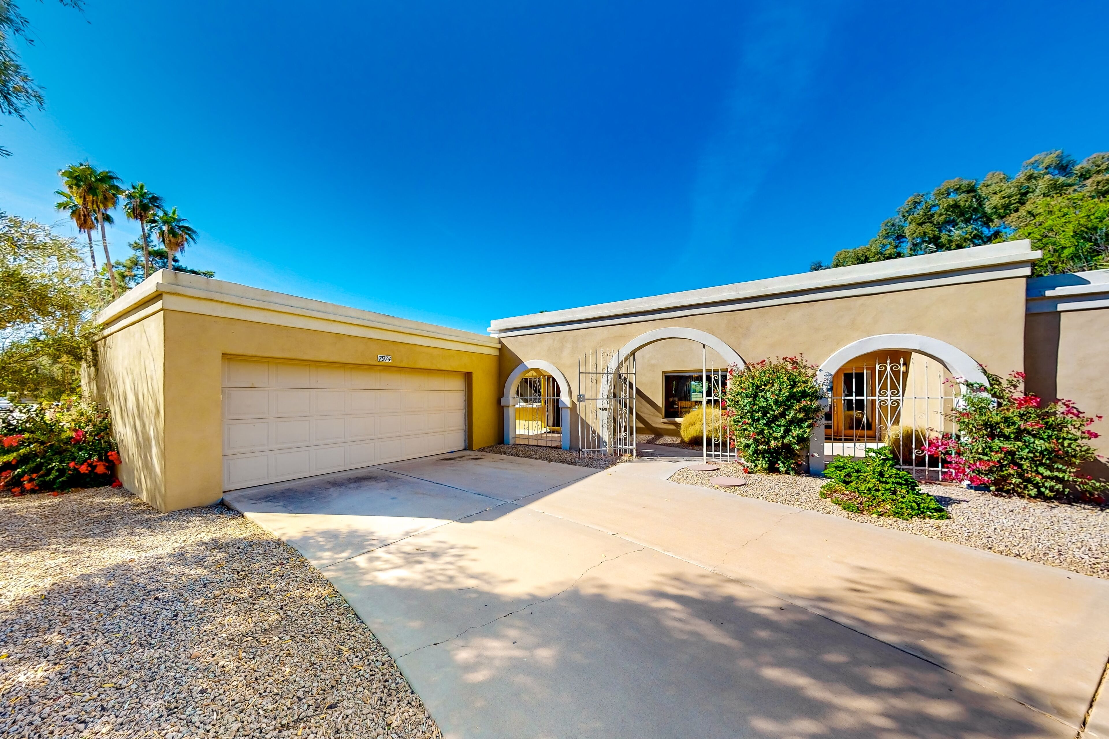 A two-story house with a garage, arched entryway, and a driveway leading to the front door.