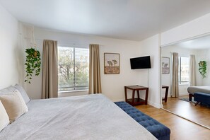 Ein Schlafzimmer mit Bett, Fernseher, kleinem Tisch und Spiegel.