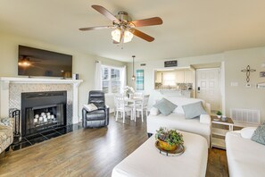 Ein geräumiges Wohnzimmer mit Kamin, Deckenventilator und Essbereich mit weißen Möbeln.