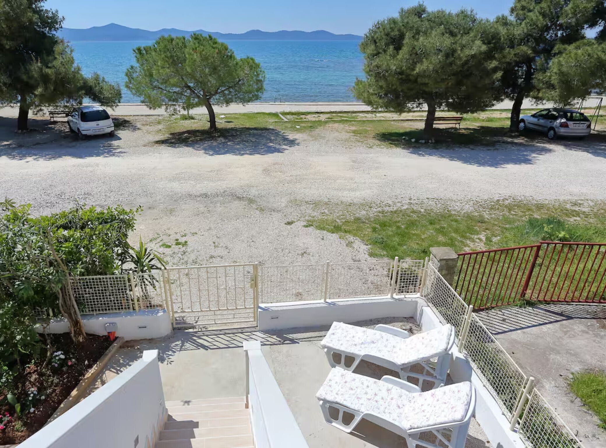 A beachside view with a pool area, including lounge chairs and a staircase leading to the pool.