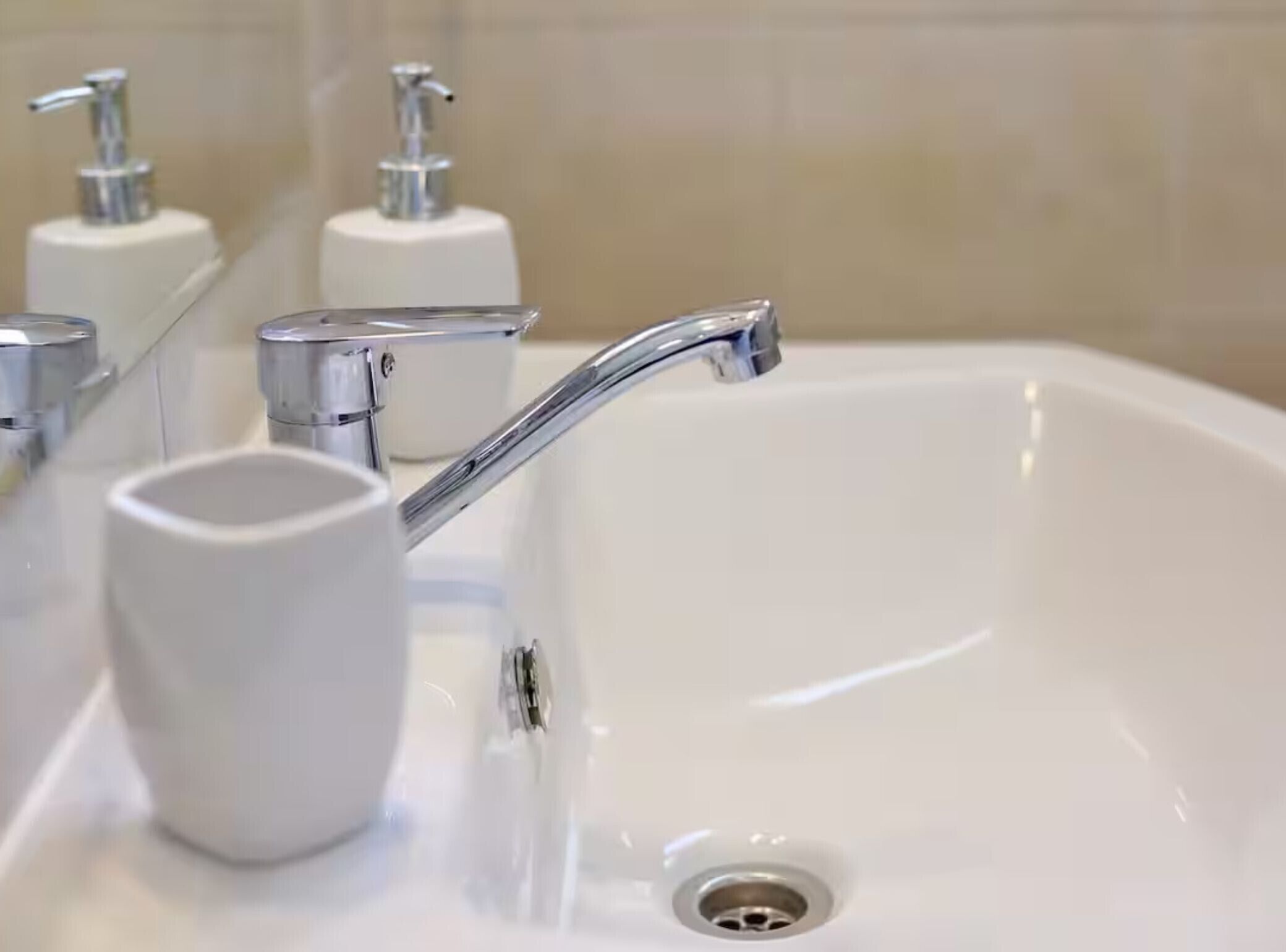 A white bathroom sink with a chrome faucet and a soap dispenser.