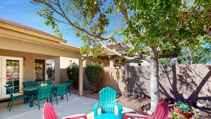 A patio with green and red chairs, a table, and potted plants. - Modern home with large yard, mountain views, & convenient location (Phoenix)
