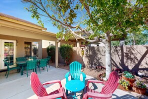 A patio with green and red chairs, a table, and potted plants. - Modern home with large yard, mountain views, & convenient location (Phoenix)