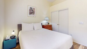A bedroom with a bed, a nightstand, a dresser, a lamp, a picture on the wall, and a door. - Modern home with large yard, mountain views, & convenient location (Phoenix)
